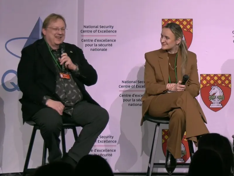 Andreas Lindenblatt und Branka Maryan auf einem Podium vor einer Wand mit dem Schriftzug „National Security Centre of Excellence“.